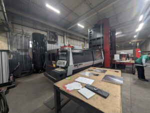 Operator-side view of an Amada ENSIS 3015 AJ fiber laser cutting machine with the control panel