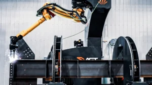 Robotic structural-steel welding systems performing AGT BeamMaster robotic structural-steel arc welding in a metal fabrication shop